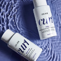 Twee flacons Color Wow Curl Wow Hooked 100% Clean Shampoo op een wateroppervlak