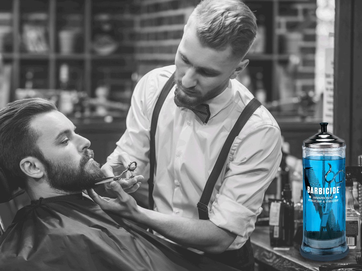 Barbier aan het werk met een Barbicide desinfectiepot op de werkplek